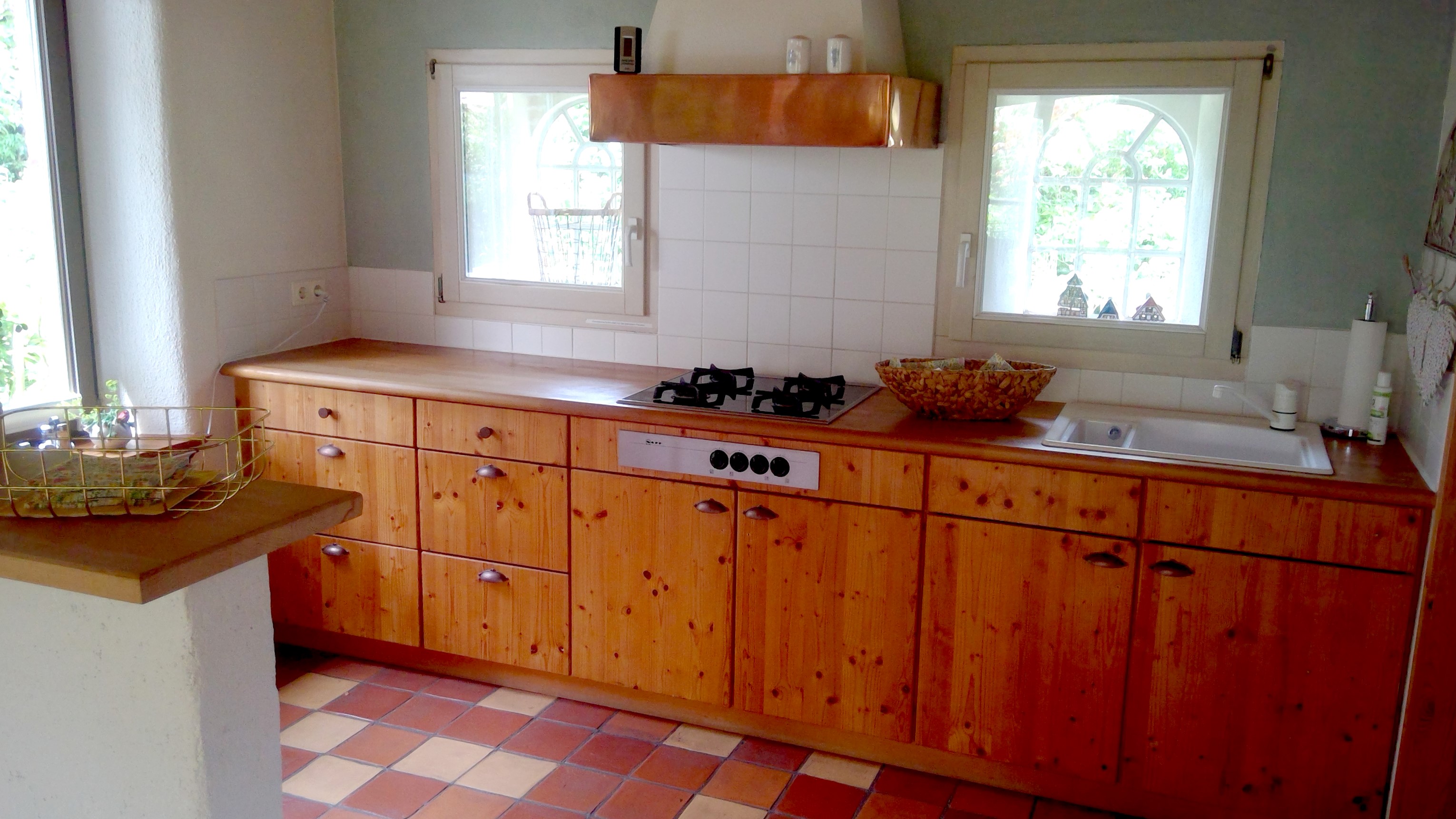 Freundliche, voll ausgestattete Küche mit Holzfronten und Arbeitsfläche.